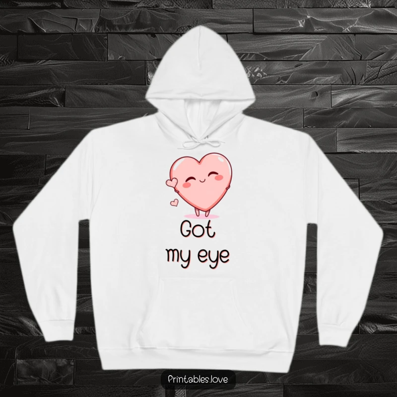 Funny hoodie with a large heart character playfully winking and a tiny heart floating, offering cozy comfort and humorous charm.